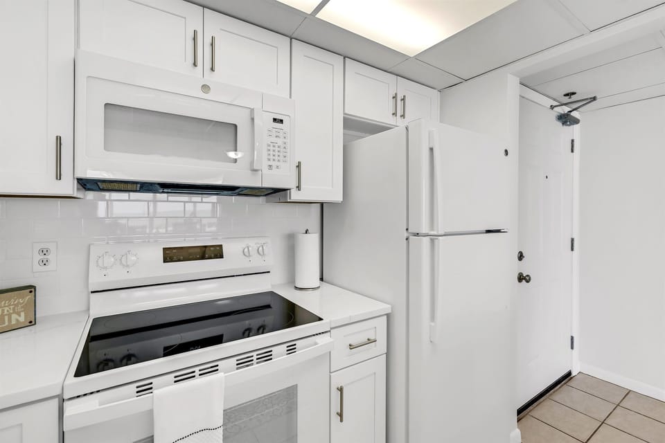 Your pristine white kitchen awaits with full-size appliances and gleaming countertops, perfect for preparing meals in comfort.