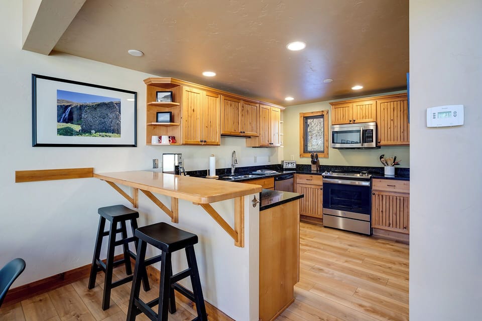 Your fully-equipped kitchen welcomes culinary adventures with warm wood cabinets, granite counters, and a breakfast bar perfect for morning coffee.