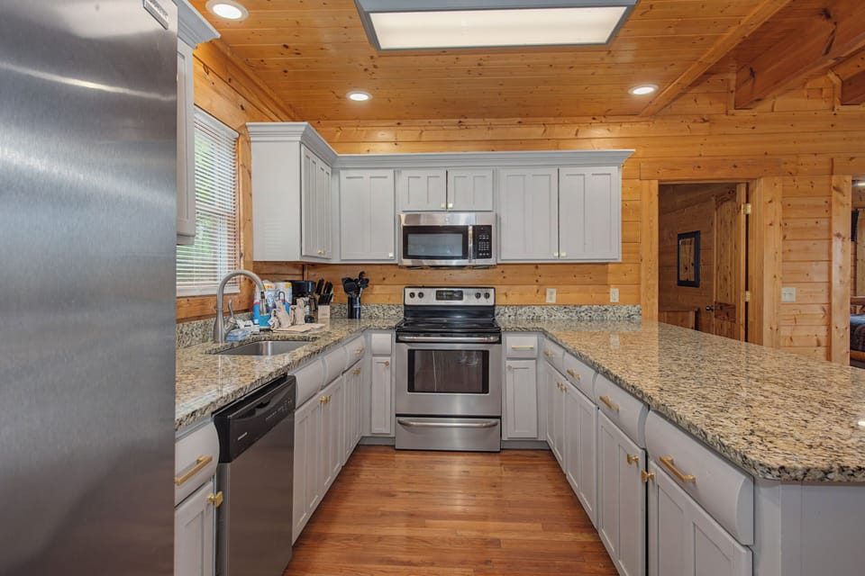 Your fully equipped kitchen awaits with granite counters, stainless steel appliances, and warm wood beams overhead for memorable meal prep.