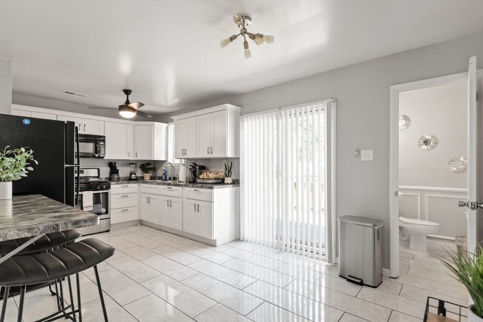 Modern kitchen featuring a ceiling fan, gas stove, oven, fridge, freezer, microwave, Keurig coffee station, and more.