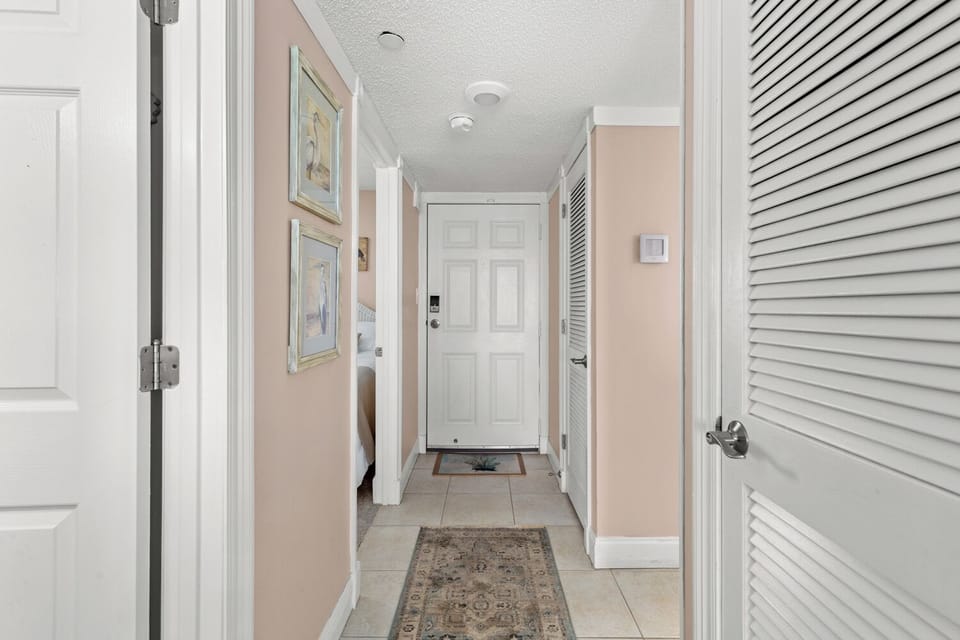 Welcoming hallway with coastal artwork and tiled floor.