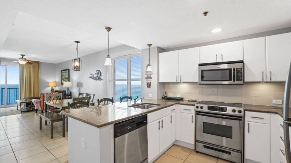 Your modern kitchen flows seamlessly into the dining and living areas, featuring granite countertops and ocean views through floor-to-ceiling windows.