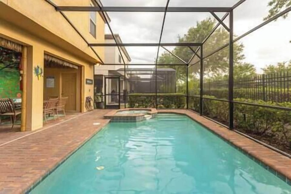 Pool deck with heated pool and spa, sound lounge chairs, and outdoor dining table.