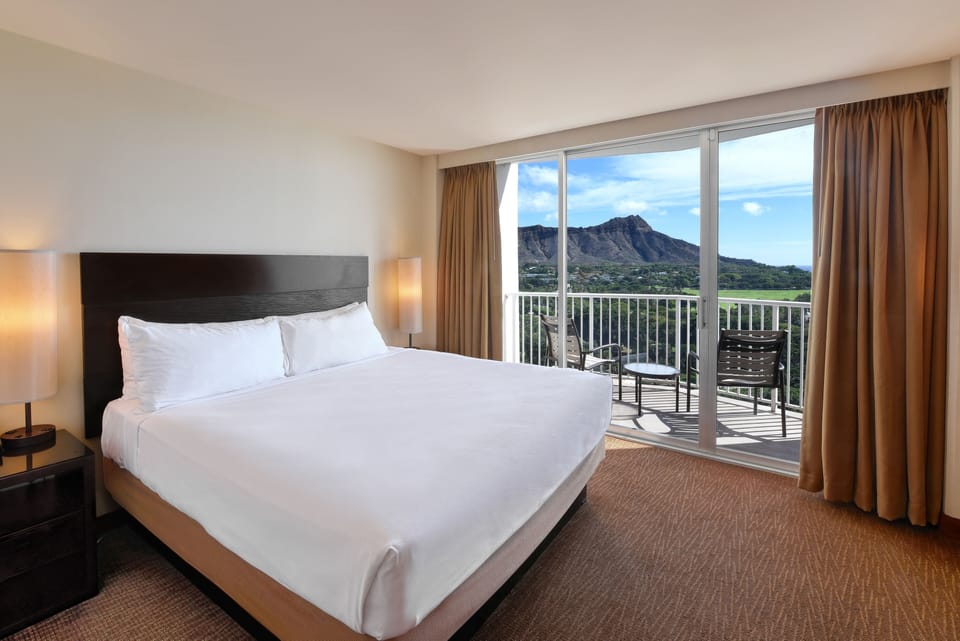 Sink into a plush king bed with breathtaking balcony scenery.