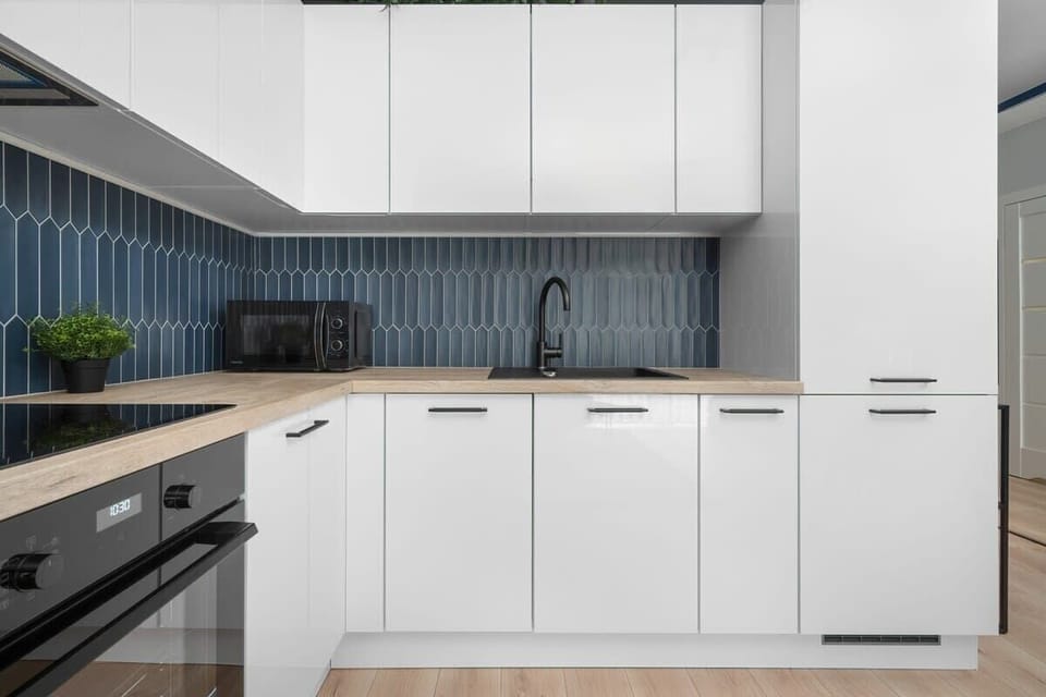 A full kitchen setup with white cabinetry and dark countertops.