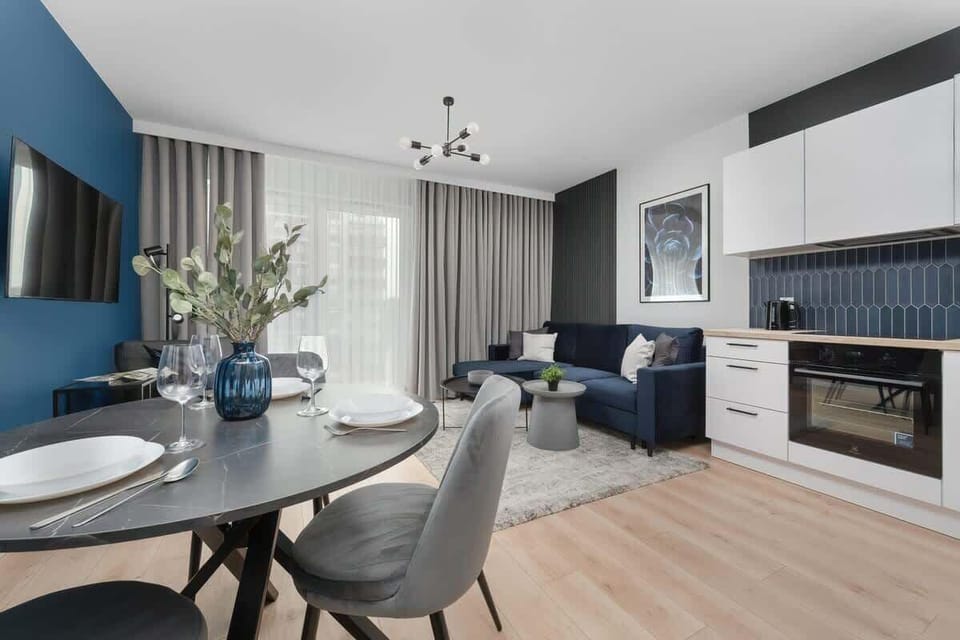 A combined dining area with a grey sofa, round dining table, and large windows.