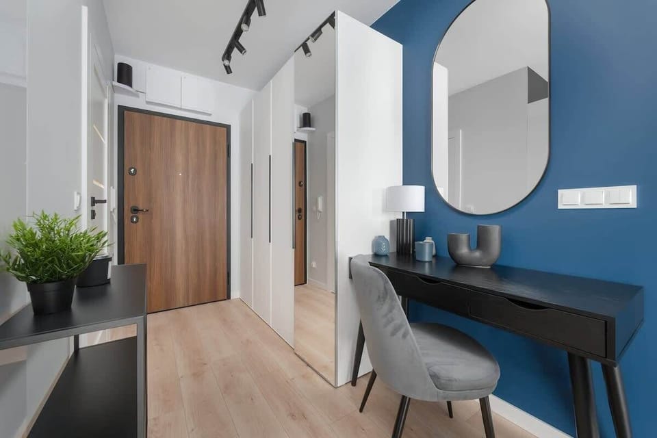 A bright entry hallway with wooden floors, a mirror, and simple decor.