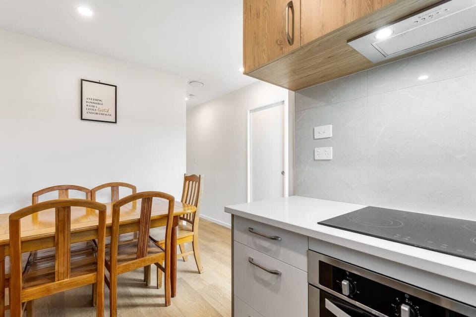 The dining table is close to the kitchen with the living room on the other side of the stairs.