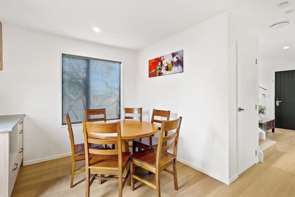 The dining table is close to the kitchen with the living room on the other side of the stairs.