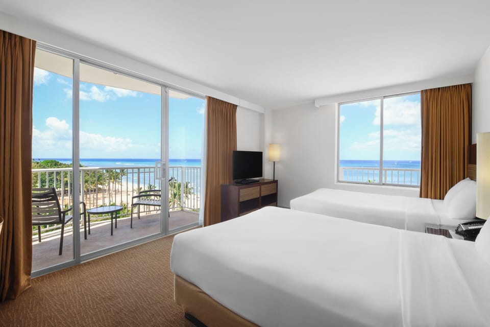 Wake to ocean breezes beside crisp linens and balcony views.
