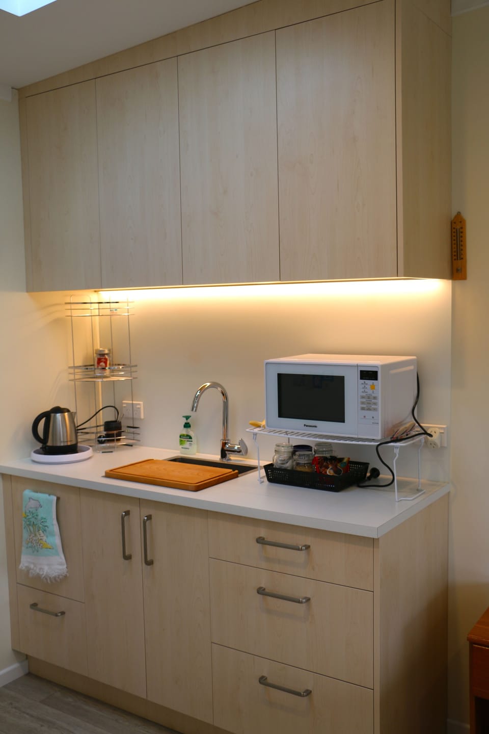 Kitchenette with full size fridge opposite this sink and cupboard setup 