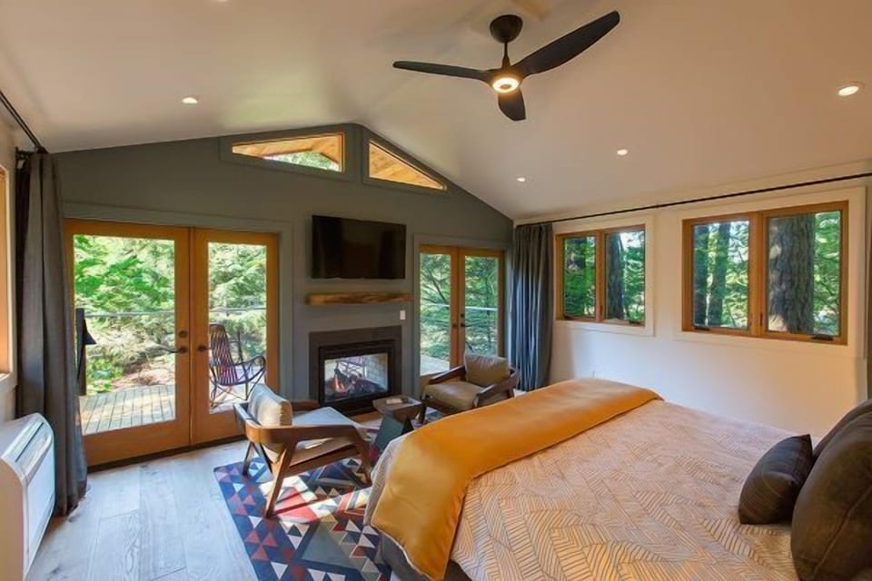 Spacious and sunlit bedroom with panoramic windows offering stunning nature views.