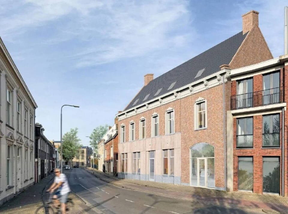 Charming street view featuring classic and modern brick architecture, large windows, and a cyclist passing by, with clear skies and greenery in the background, creating a blend of tradition and modernity.