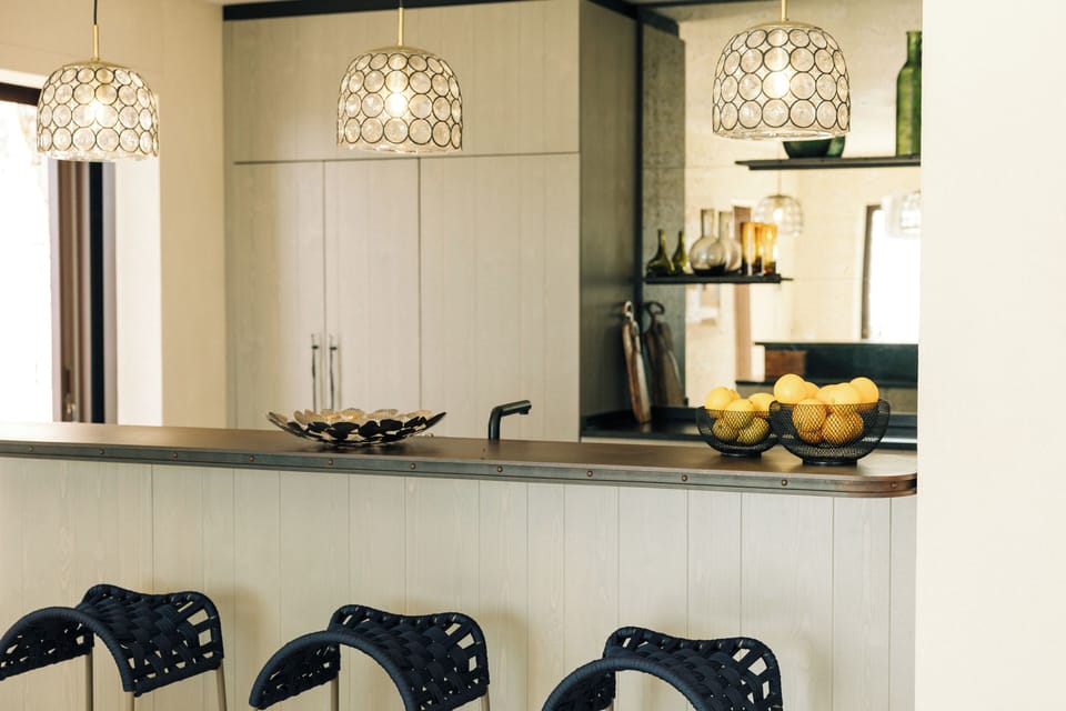 Stylish kitchen area with designer bar stools, pendant lighting and oranges.