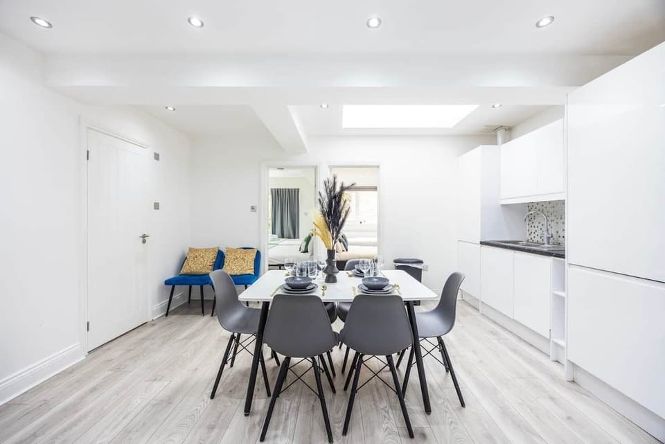 Modern dining area with sleek grey seating, a white dining table, and premium laminate floors. Features include a dedicated en-suite washroom, integrated recessed lighting, and climate control.