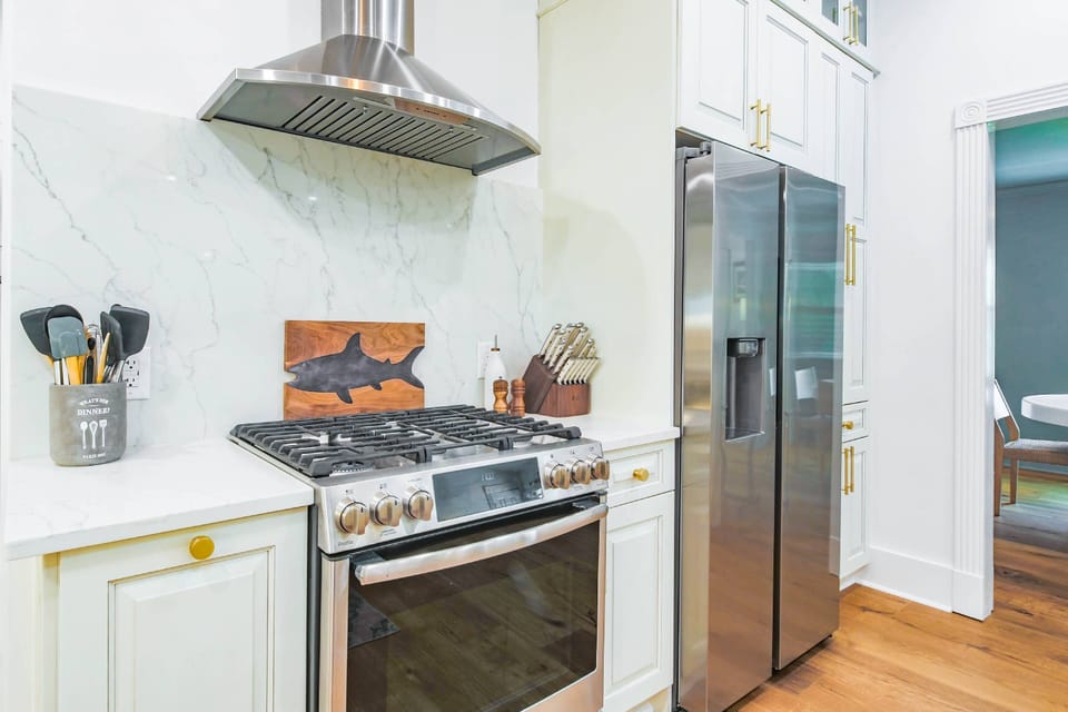 The kitchen features a stainless steel range, refrigerator and hood.