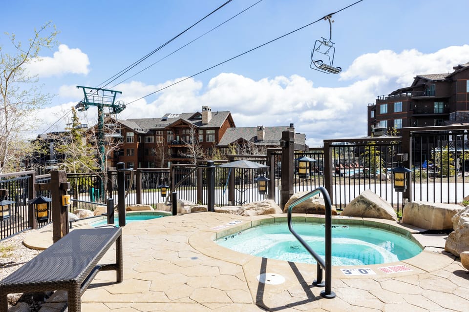 Unwind in bubbling hot tubs beneath the ski lift, surrounded by mountain architecture and bluebird skies.