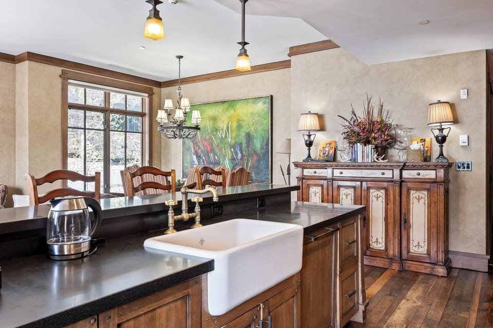 - Enjoy meals beneath an iron chandelier in a warm, sunlit dining space with mountain views
- Rustic buffet and curated decor add vintage charm and cozy ambiance
- Farmhouse sink and sleek counter blend old world style with modern ease