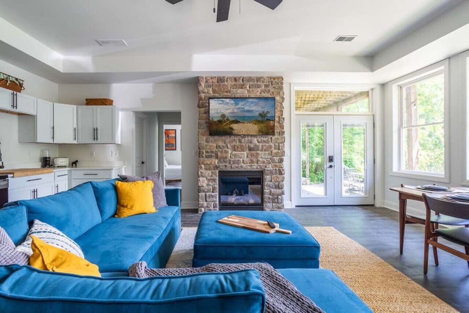 Unwind in our bright living room with expansive windows, cozy stone fireplace, & plush sectional sofa. Perfect for relaxing after exploring Indiana Dunes National Park. Enjoy direct access to the outdoor patio with hot tub, grill, firepit, & dome.