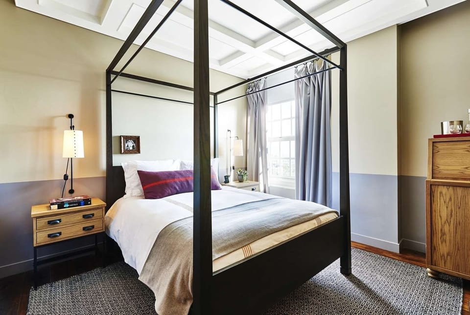 Unwind in crisp linens beneath the striking four-poster frame.