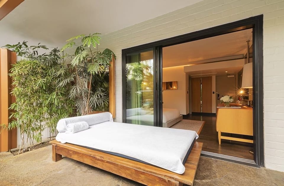 Lounge outdoors on a plush daybed beside tropical greenery