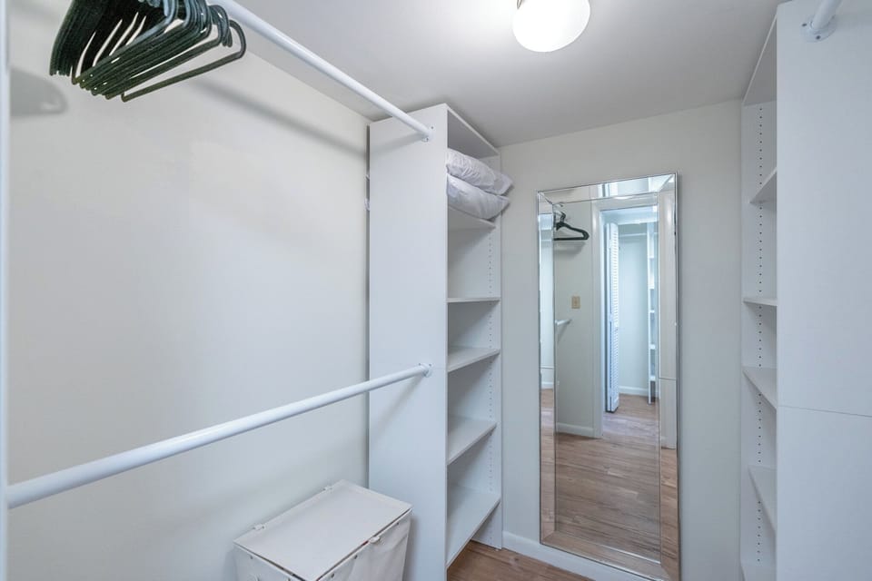 Newly remodeled master closet with full length mirror, shelves, and hangers 