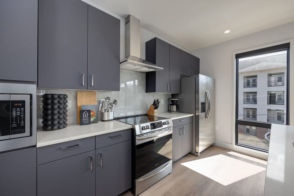 Unit 1: Fully equipped kitchen stocked with basic cooking essentials. Includes stainless steel appliances and kitchen island seating.
