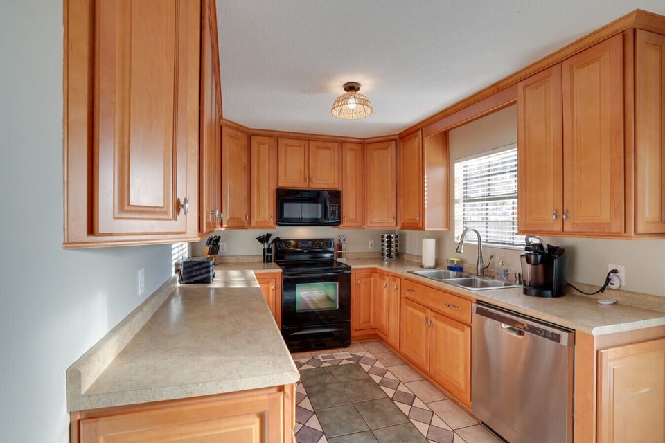 A well-lit kitchen with wooden cabinetry, black appliances, and plenty of counter space for cooking.