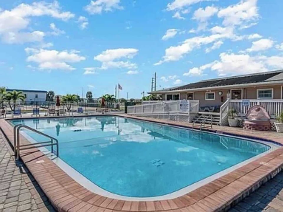 Outdoor pool area with clear water and surrounding seating under a bright sky