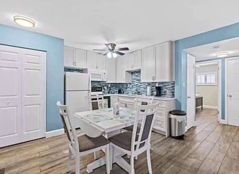 Modern kitchen with white cabinetry and a dining area for four.