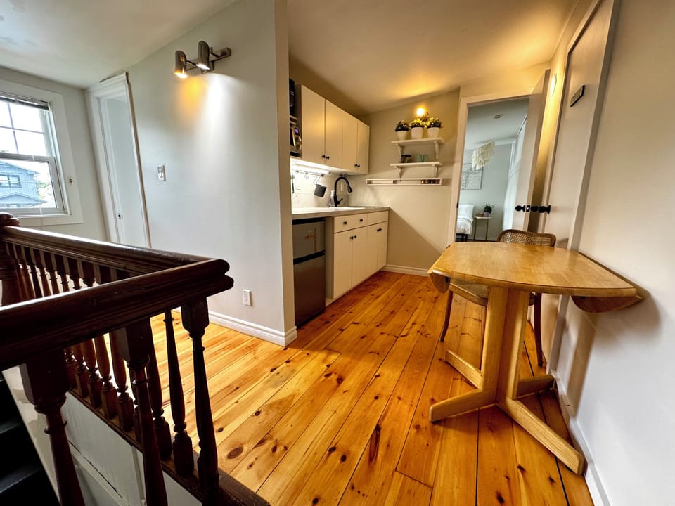 Fridge, cooktop, microwave, toaster, Nespresso, blender, utensils, dining area.