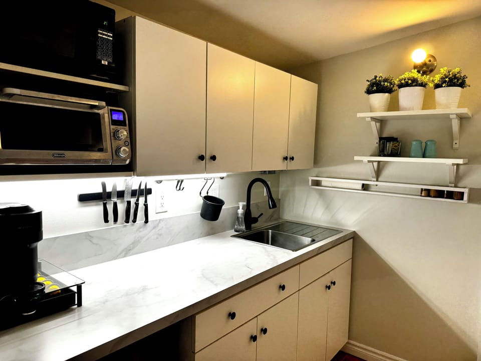 Fridge, cooktop, microwave, toaster, Nespresso, blender, utensils, dining area.