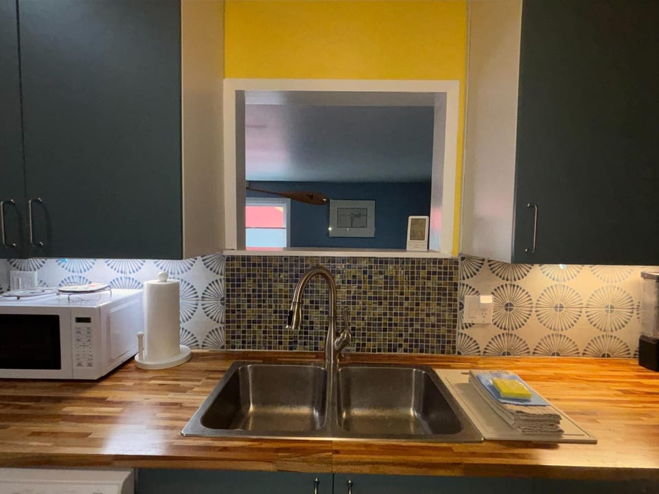 A double stainless steel sink set in butcher block counters beneath blue mosaic tile and patterned backsplash.