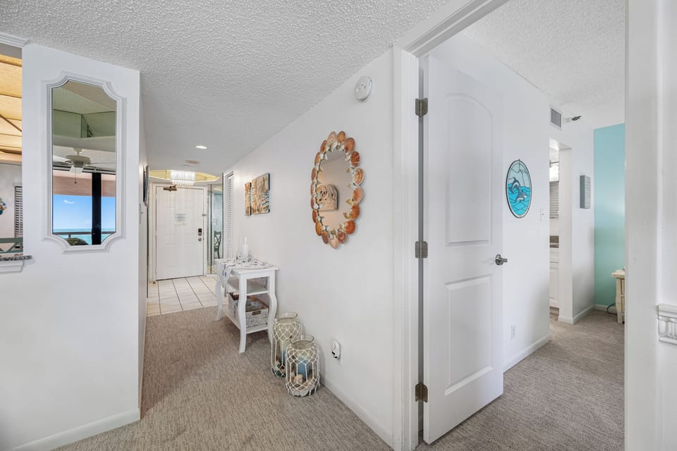 Carpeted corridor with coastal décor and bedroom access.