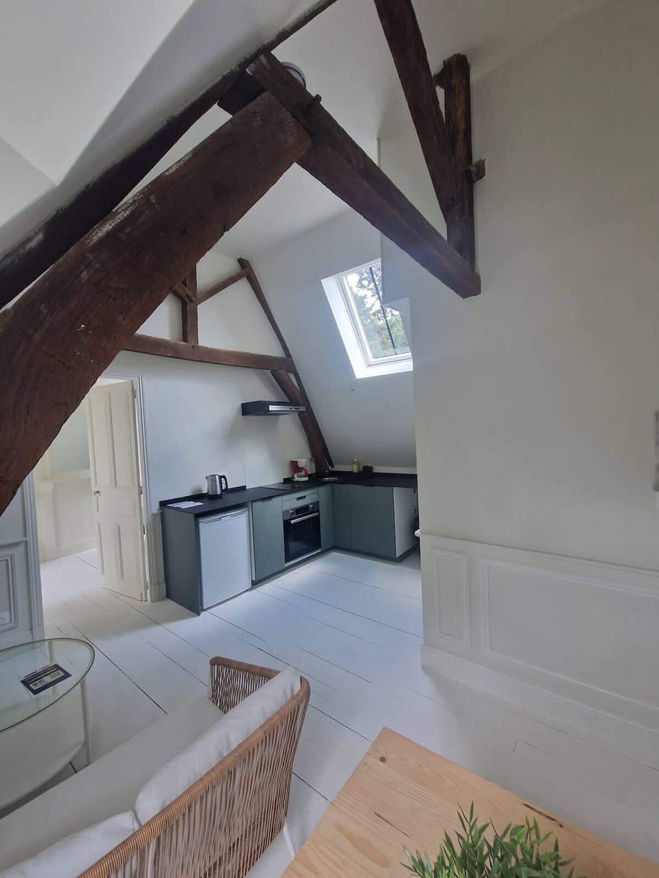 Salon avec canapé et coin repas pour deux personnes, ouvert sur la cuisine.