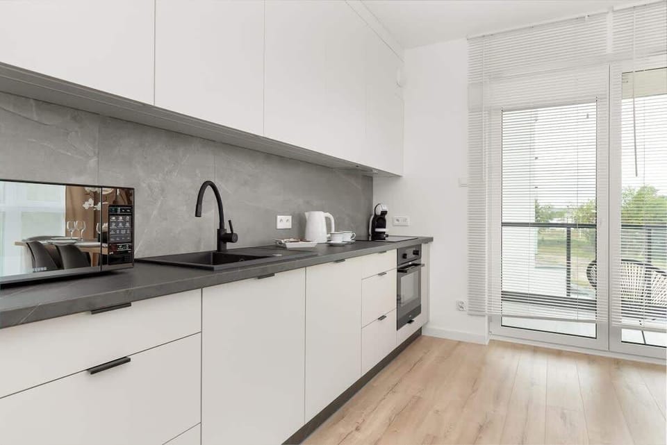 A bright kitchen with a large window provides a comfortable space for cooking, where natural light highlights the modern finishes.