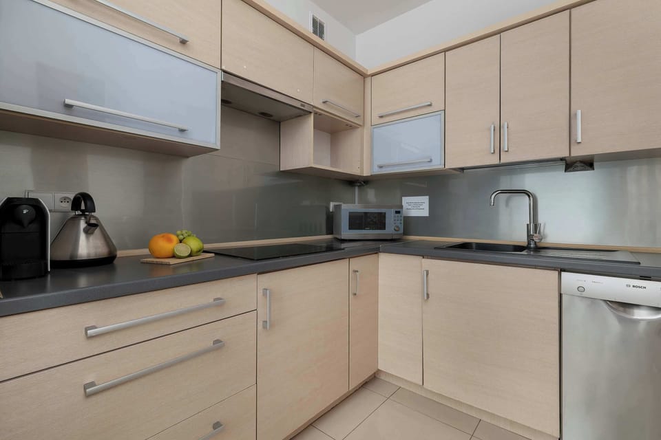 Fully equipped modern kitchen with light wood cabinets and built-in appliances.