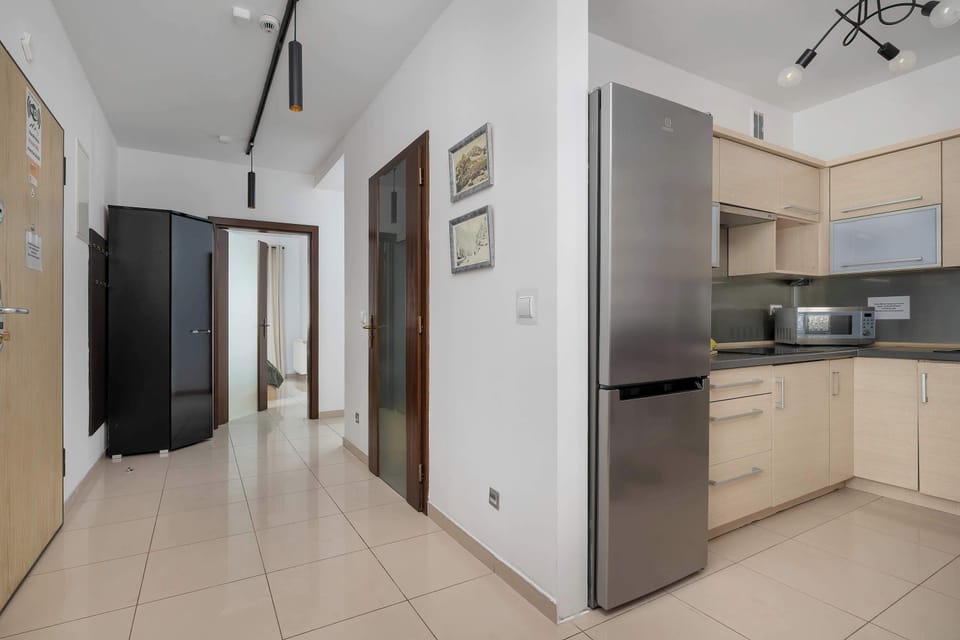 Fully equipped modern kitchen with light wood cabinets and built-in appliances.