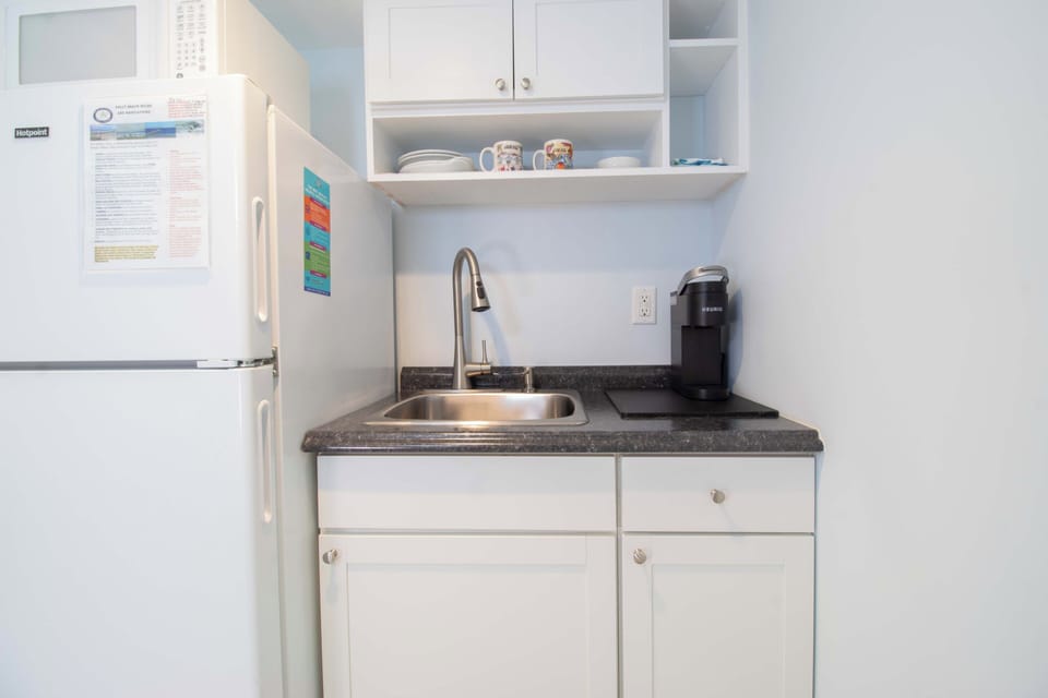 Your bright kitchenette features crisp white cabinetry, granite countertops, and a coffee maker ready for your morning brew.