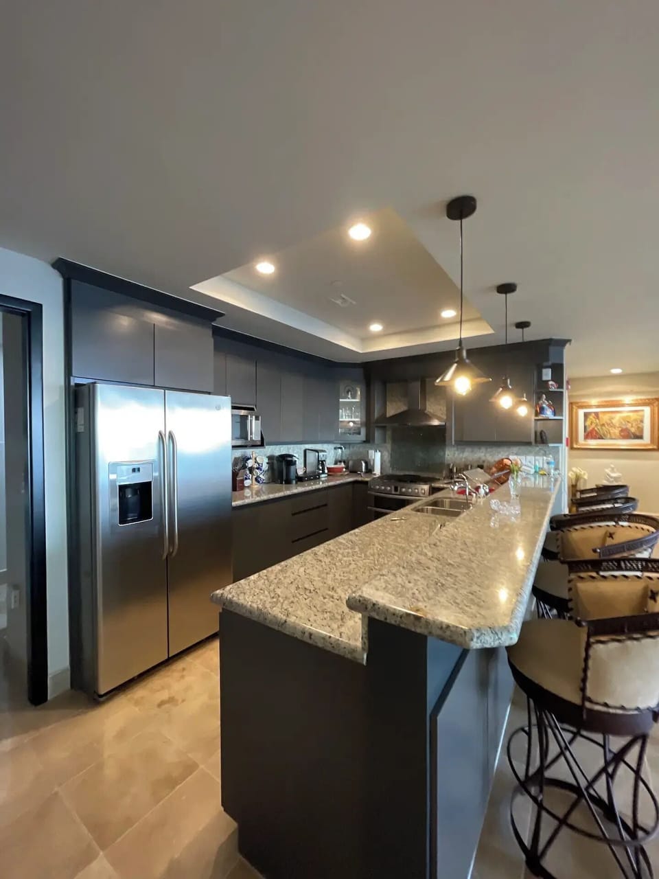 Fully equipped kitchen with granite counter and comfortable stools.