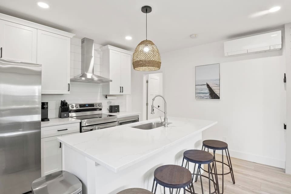 Welcome to your dream kitchen! This contemporary space is designed for both function and style, featuring a large island with bar seating and high-end appliances. The minimalist design and bright white cabinetry create an open, fresh atmosphere perfe