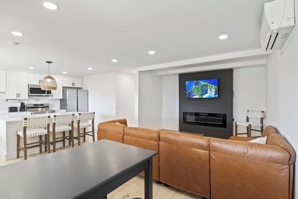 Unwind in this beautifully designed living room featuring a modern fireplace and a comfortable sectional sofa. The neutral tones and contemporary décor create a relaxing and inviting atmosphere, perfect for cozy nights in. Enjoy your favorite shows o