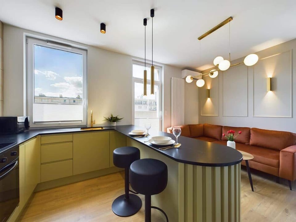 Contemporary kitchen with black countertop, light wood flooring, and minimalistic design.