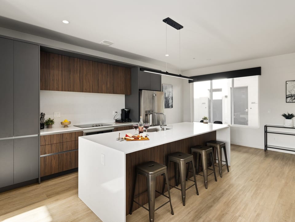 Unit 2 (1st Floor): Fully equipped modern kitchen featuring culinary essentials, stainless steel appliances, island bar seating, and a dining area.