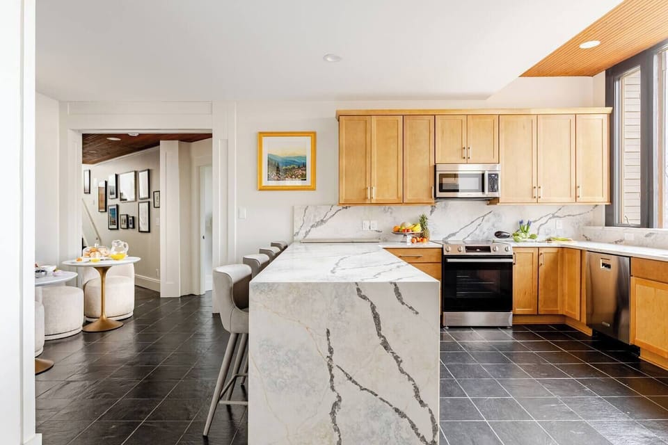 Gaze out at the best kitchen mountain view in Asheville while enjoying the multicolored patterns of our Brazilian quartzite-inspired kitchen, designed with dramatic veins of grey, navy, and caramel on a white canvas.