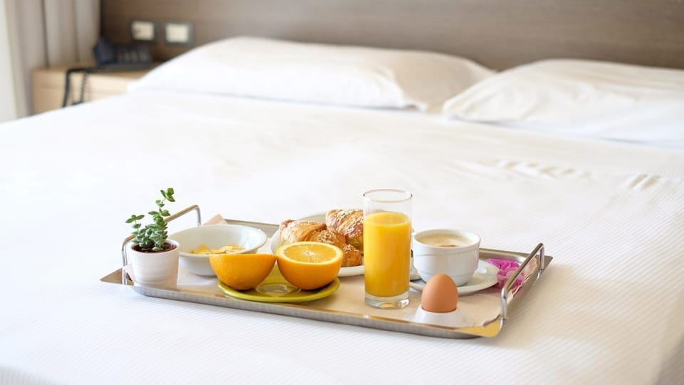 Wake up to breakfast in bed on crisp white linens—fresh orange juice, warm pastries, and coffee await your perfect morning.