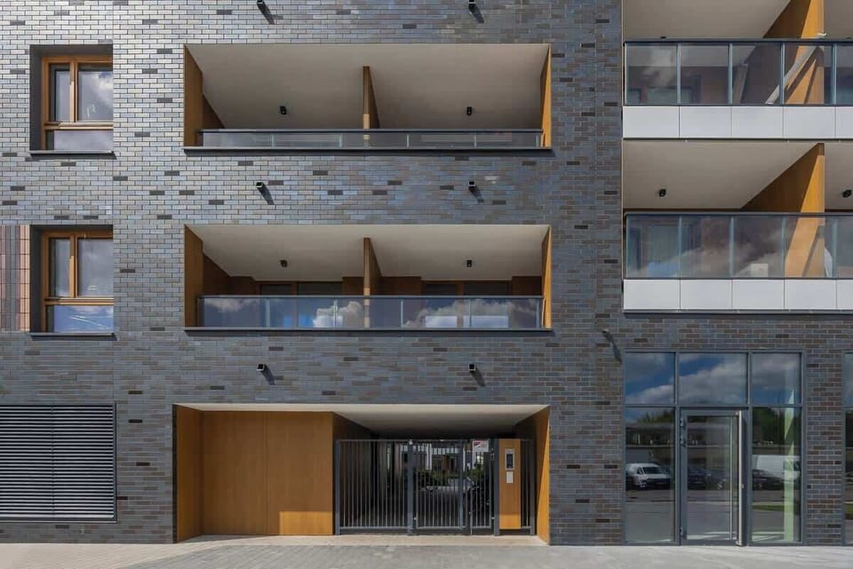 Modern apartment facade with grey and wood finish, glass balconies, and clean lines.