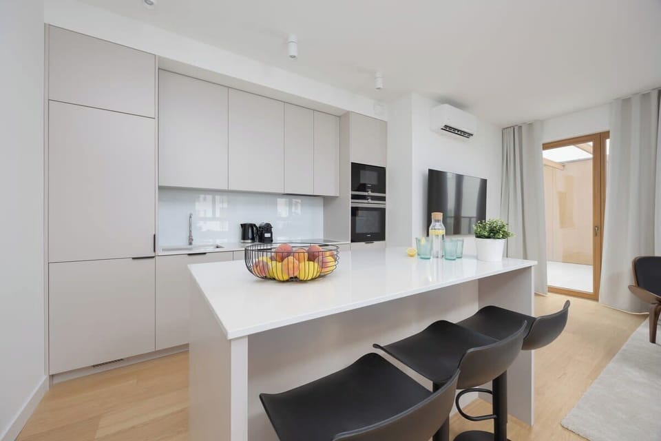 Sleek kitchen with white cabinets, island with barstools, and modern appliances.