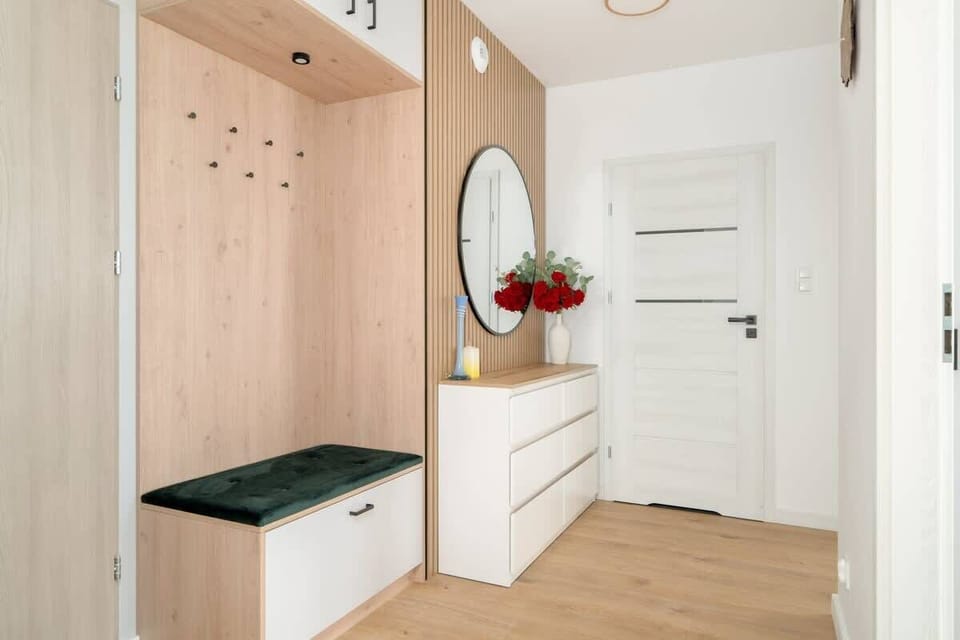 A view of the entryway with wooden cabinetry and a mirror.