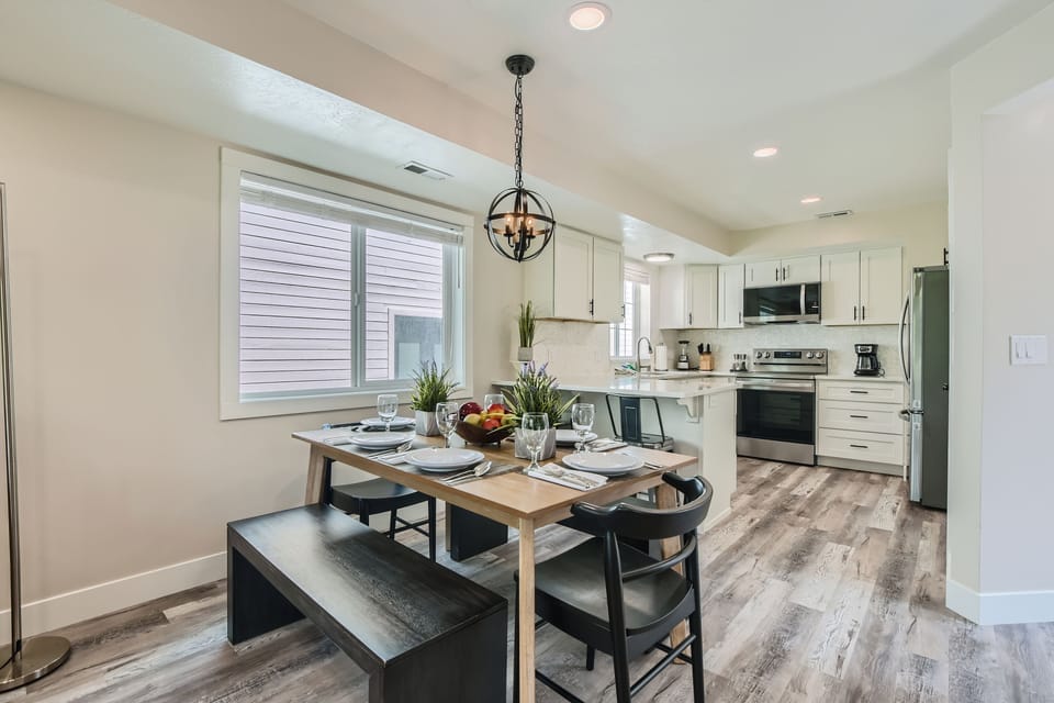 Enjoy meals in this modern dining area featuring a unique orb light fixture, wood table, and bench seating. Seamlessly connected to the fully-equipped kitchen for your Park City getaway.